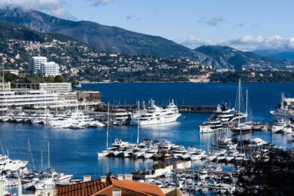 Monaco kikötője jachtokkal, mögötte a hegyoldalra épült város