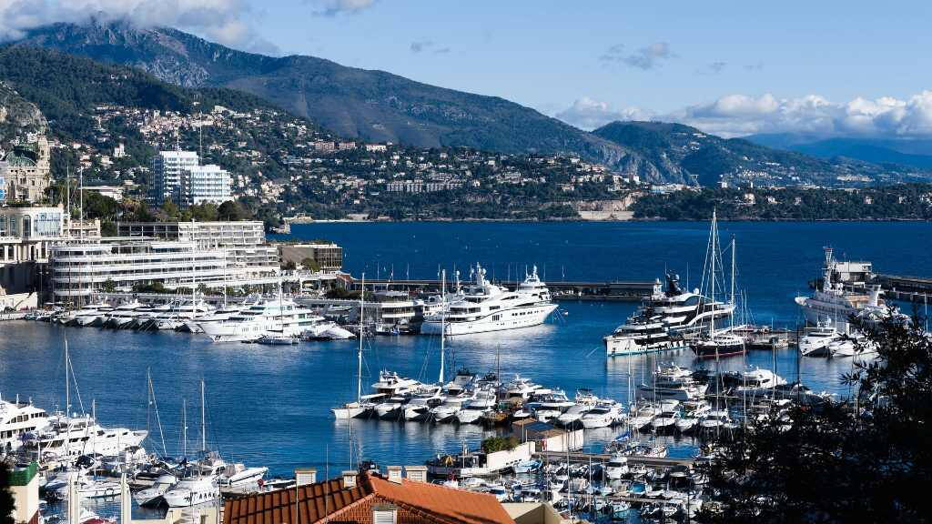Monaco kikötője jachtokkal, mögötte a hegyoldalra épült város