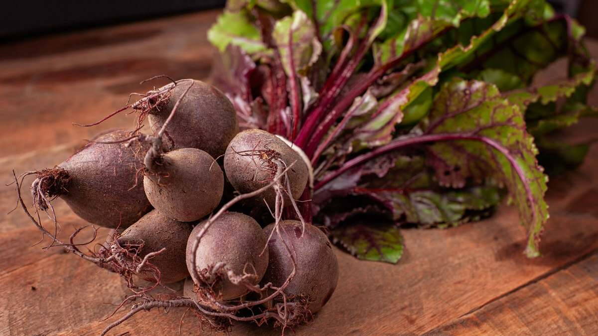 Egész, földes cékla gumók egy fa asztalon